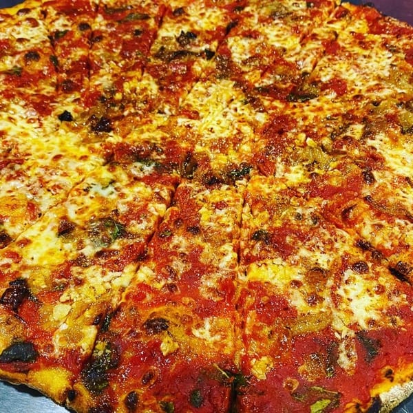 A close-up of a freshly baked, sliced Casa Pizzeria craft pizza with melted cheese and red sauce.