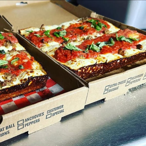 Two rectangular deep-dish Casa Pizzeria craft pizzas with red sauce, cheese, and basil in open boxes.