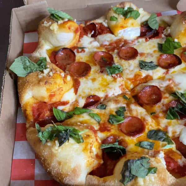 Close-up of a Casa Pizzeria pepperoni pizza with fresh basil and cheese in a delivery box.