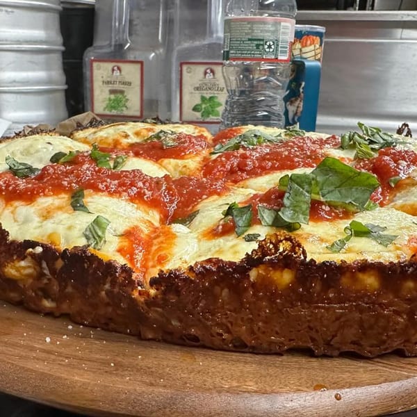 A deep-dish pizza from Casa Pizzeria, topped with melted cheese, red sauce, and fresh basil.