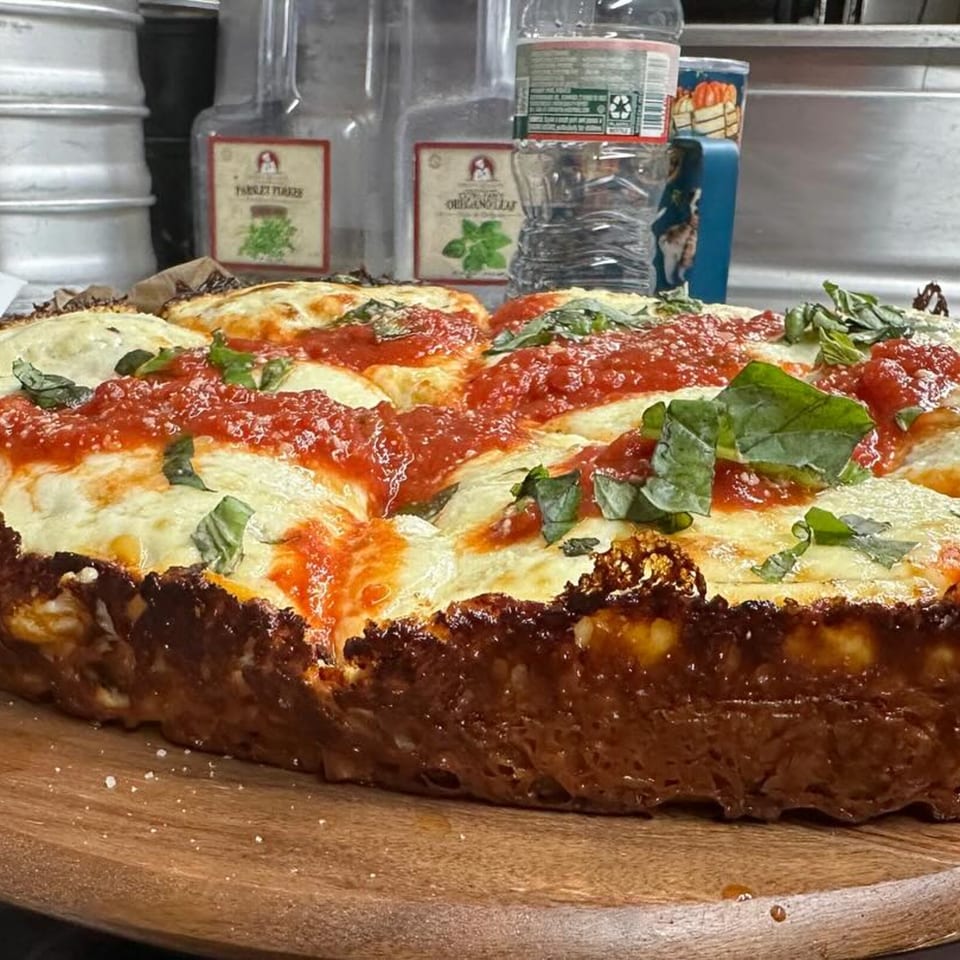 A deep-dish pizza from Casa Pizzeria, topped with melted cheese, red sauce, and fresh basil.