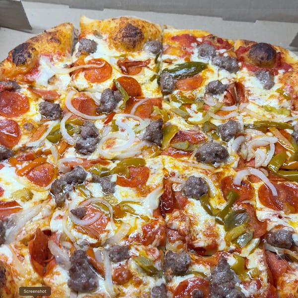 Close-up of a Casa Pizzeria craft pizza with pepperoni, sausage, onions, and green peppers.