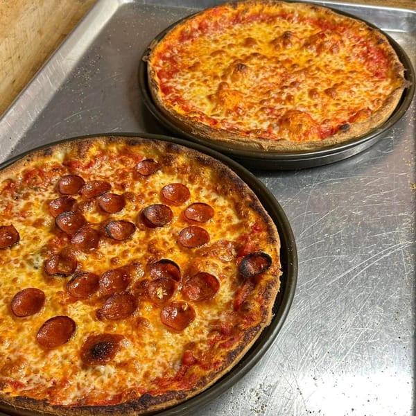 Two freshly baked Casa Pizzeria craft pizzas, one pepperoni and one cheese, on a metal tray.
